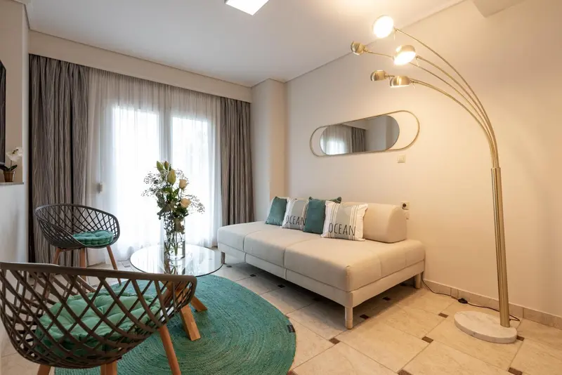 Un salon clair avec un canapé, des fauteuils et une lampe sur pied.