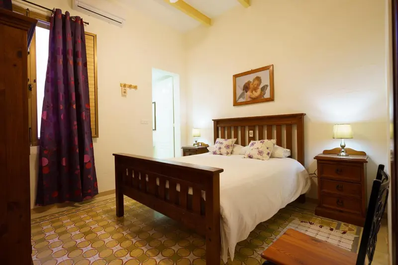 Une chambre lumineuse avec un grand lit et des meubles en bois.