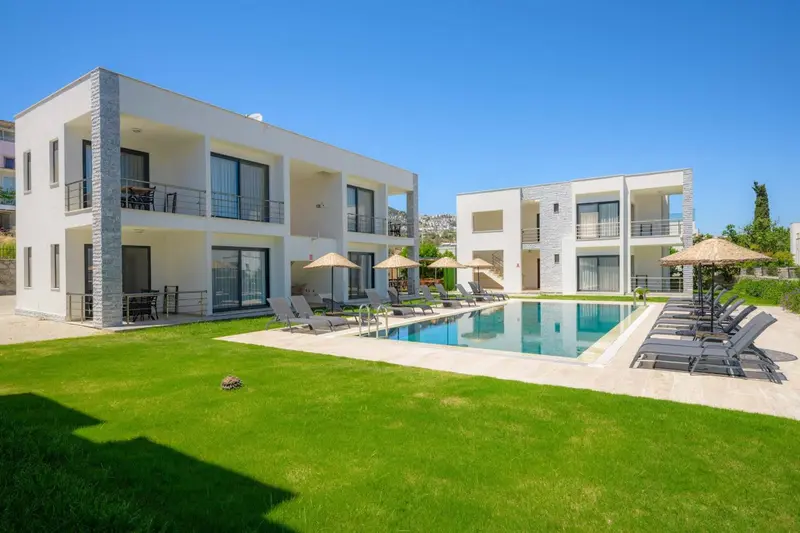 Bâtiment blanc moderne avec piscine et pelouse verdoyante.