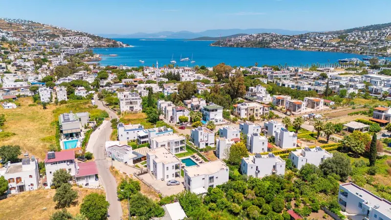 Vue aérienne d'un village côtier avec des maisons blanches et une végétation luxuriante.