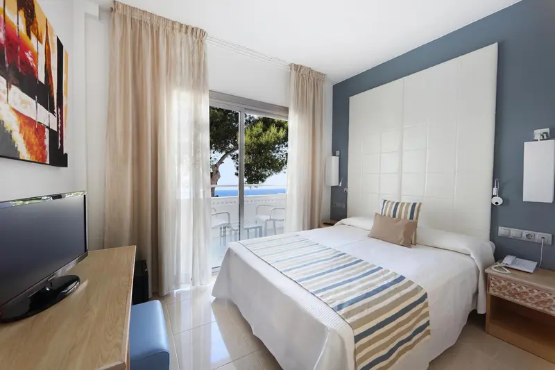 Chambre lumineuse avec un grand lit et vue sur la mer.