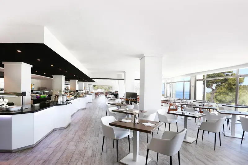 Une salle lumineuse avec un buffet et des tables pour les repas.