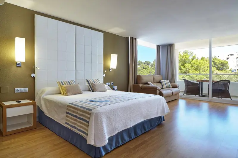 Une chambre lumineuse avec un grand lit et un coin salon.