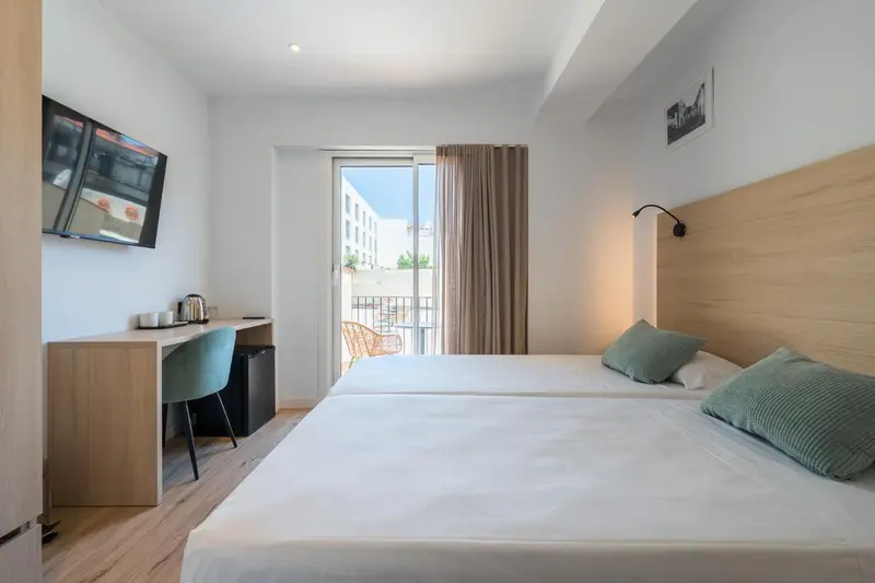 Chambre lumineuse avec lits jumeaux et balcon.