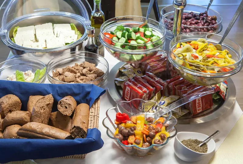 Présentation de salades, de fromages et de pains variés sur un buffet.