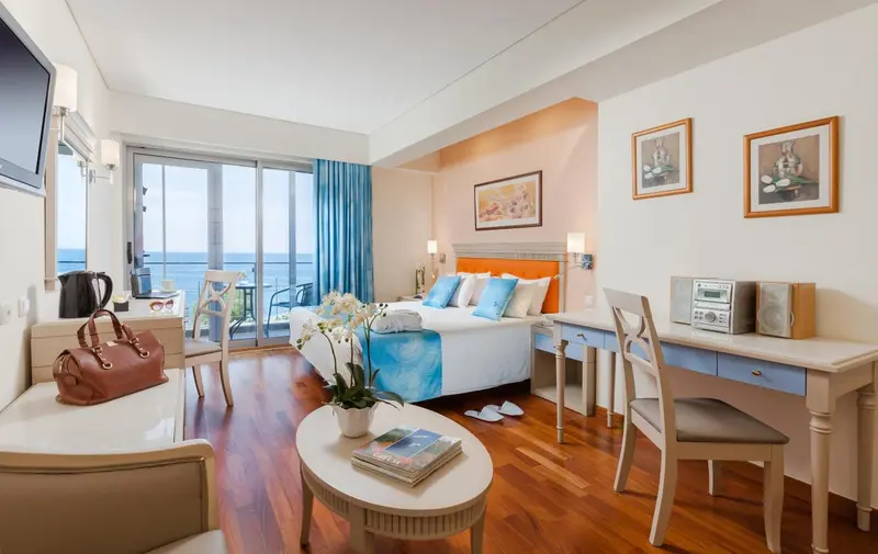 Chambre lumineuse avec un lit double et une vue sur la mer.