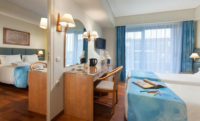 Une chambre lumineuse avec deux lits et un bureau.