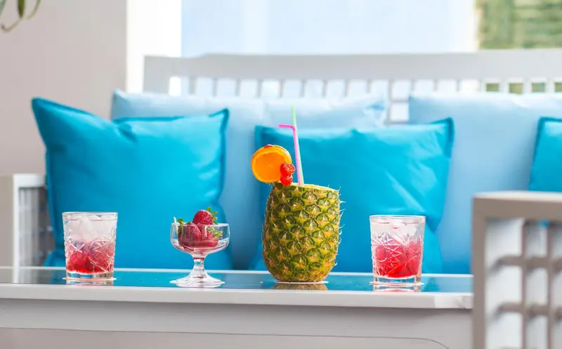 Des cocktails colorés sont servis sur une table basse devant des coussins bleus.
