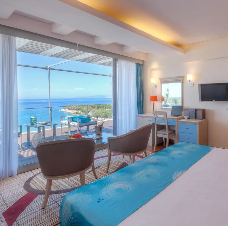 Chambre lumineuse avec vue sur la mer depuis une grande baie vitrée.