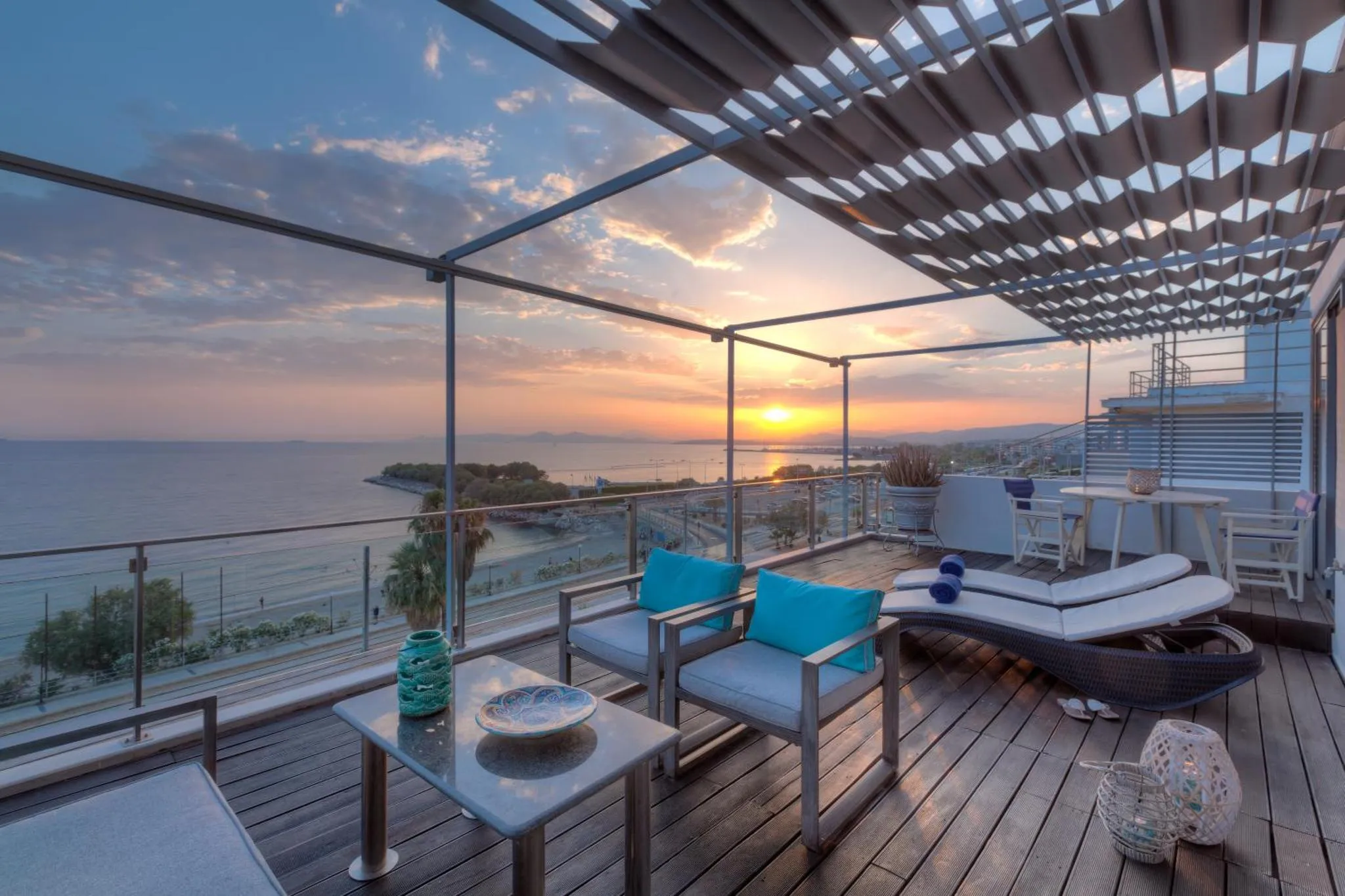 Terrasse aménagée avec mobilier de détente et vue sur la mer au coucher du soleil.