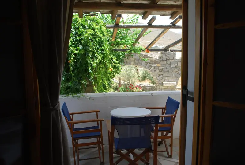 Une table ronde et deux chaises se trouvent sur une terrasse ombragée.