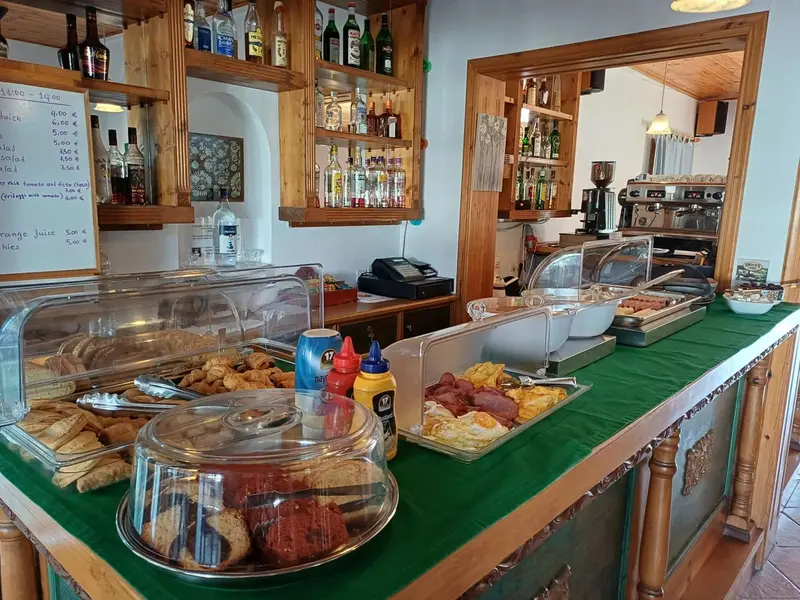 Un comptoir de bar et une vitrine réfrigérée présentent des pâtisseries et des boissons.