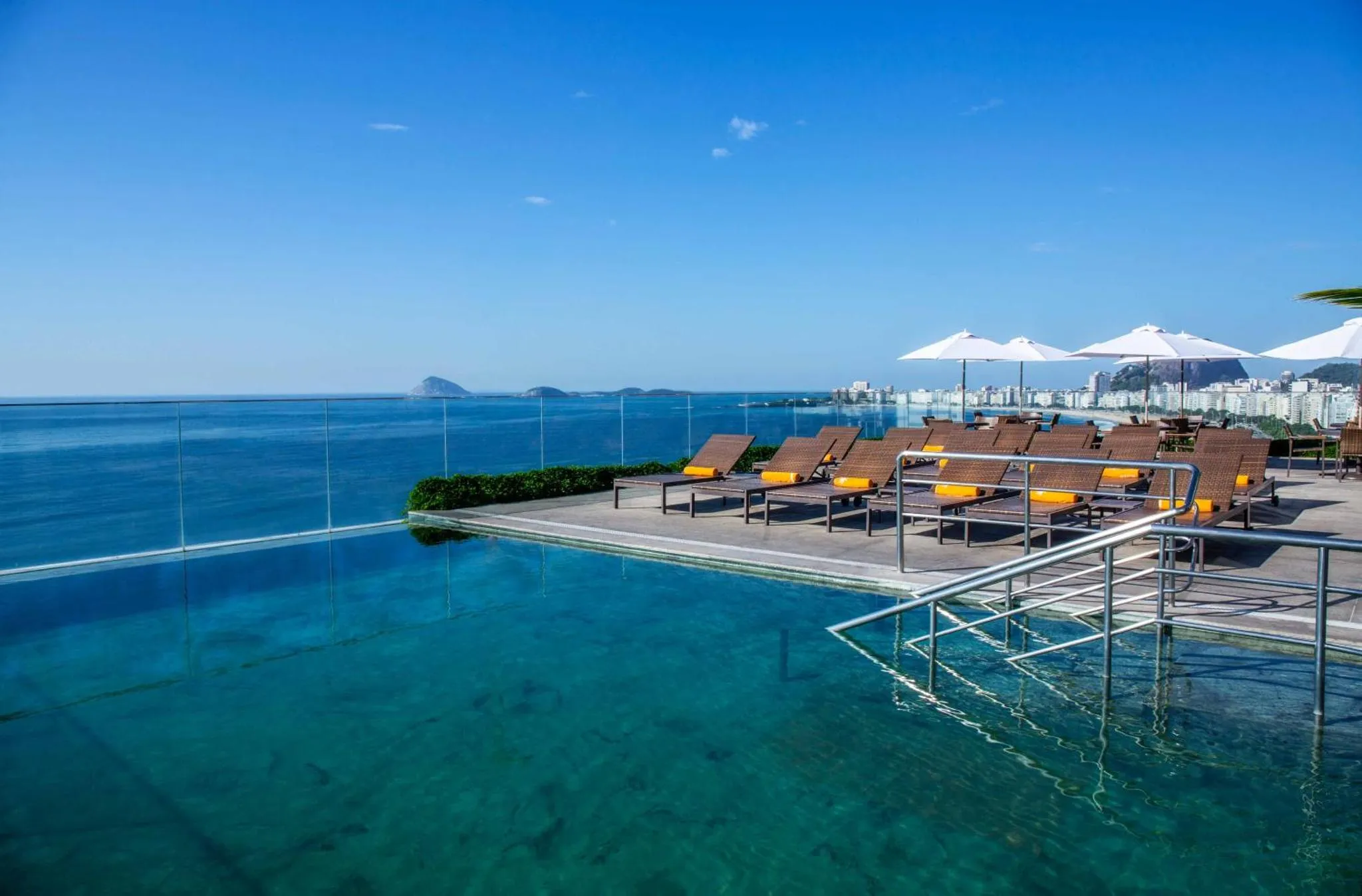 Terrasse avec transats et piscine à débordement donnant sur la mer.