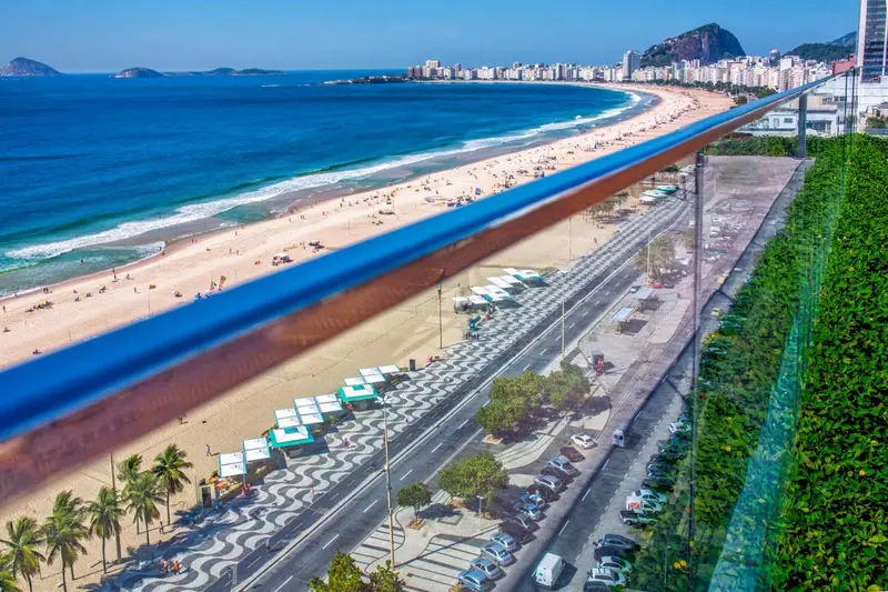 Vue aérienne d'une plage urbaine bordée d'une promenade animée.
