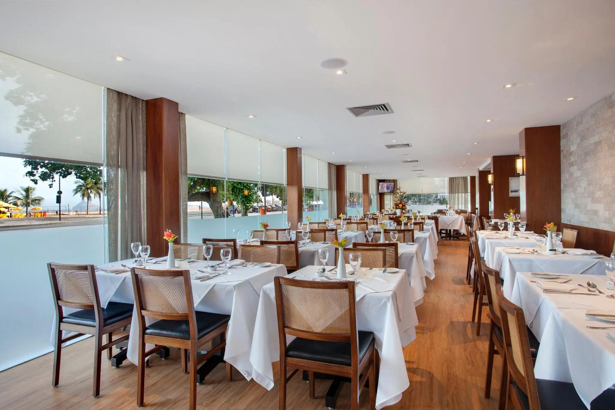 Une salle lumineuse avec des tables dressées pour un repas.