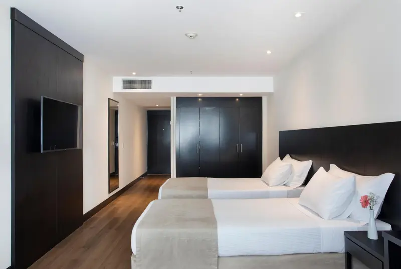 Une chambre moderne avec un grand lit et un téléviseur mural.