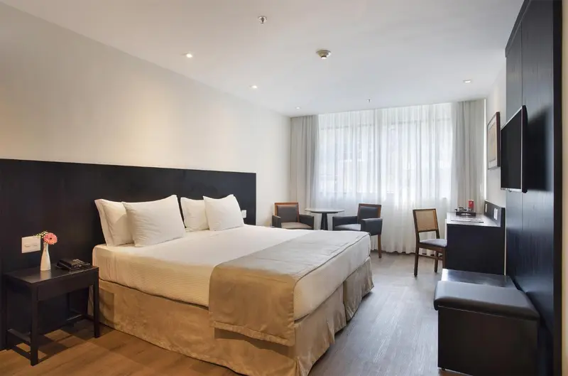 Une chambre lumineuse avec un grand lit et un coin salon.