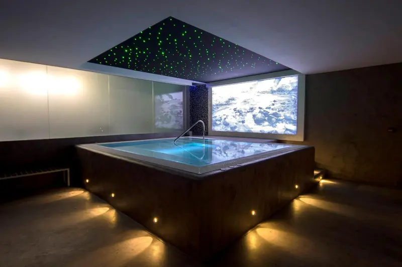 Jacuzzi rectangulaire avec un écran mural affichant un paysage marin.