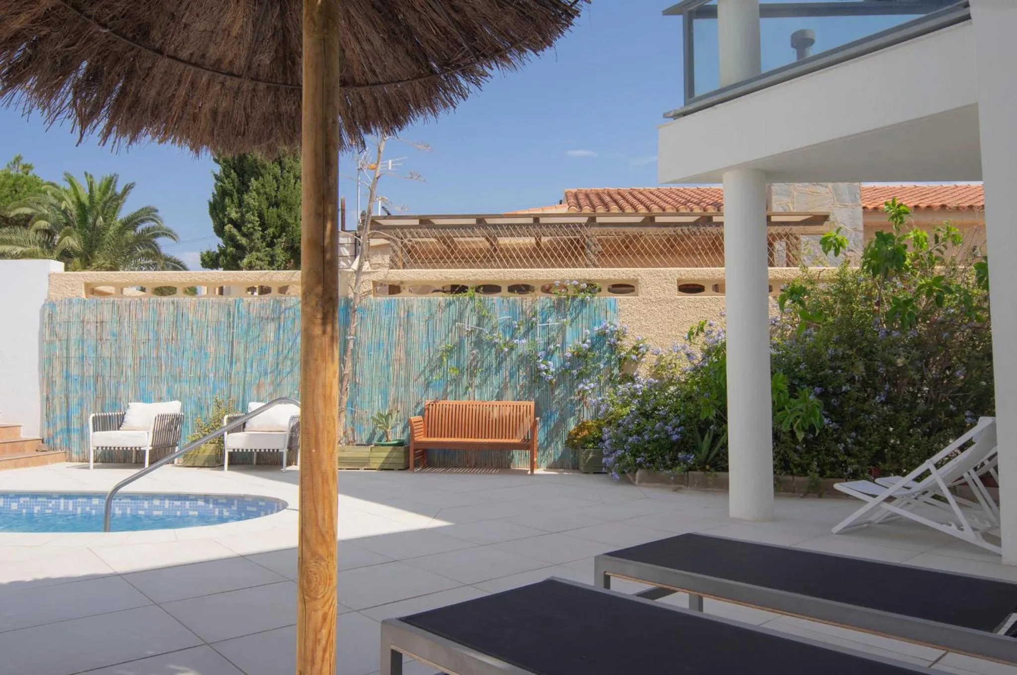 Terrasse avec mobilier de jardin et piscine ensoleillée.
