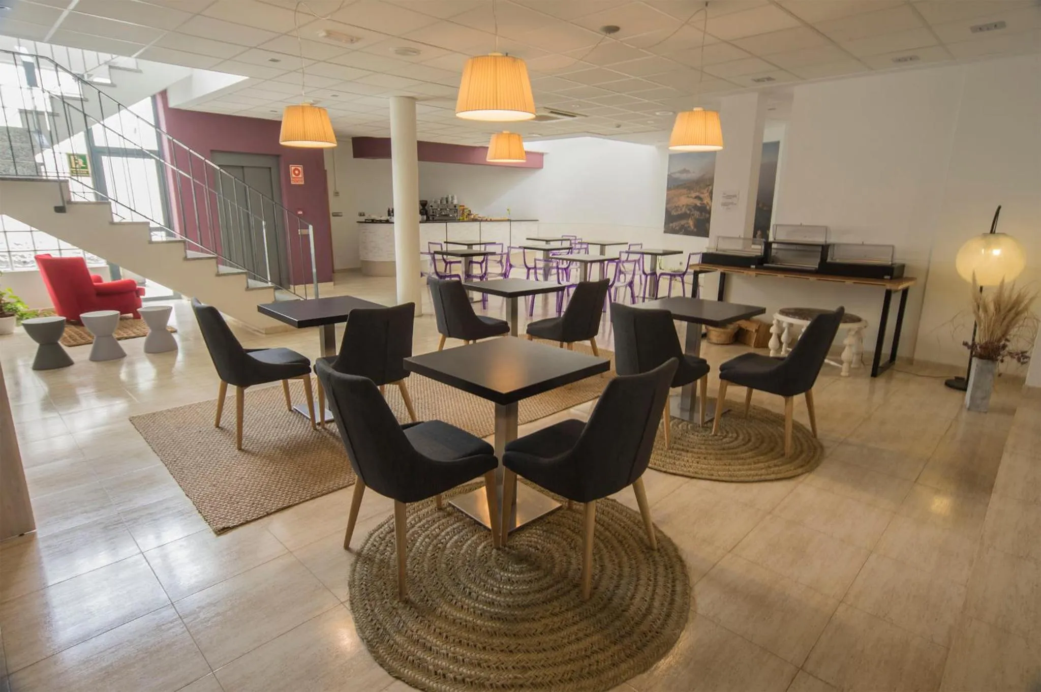 Une salle lumineuse avec des tables et des chaises disposees sur un sol carrelé.