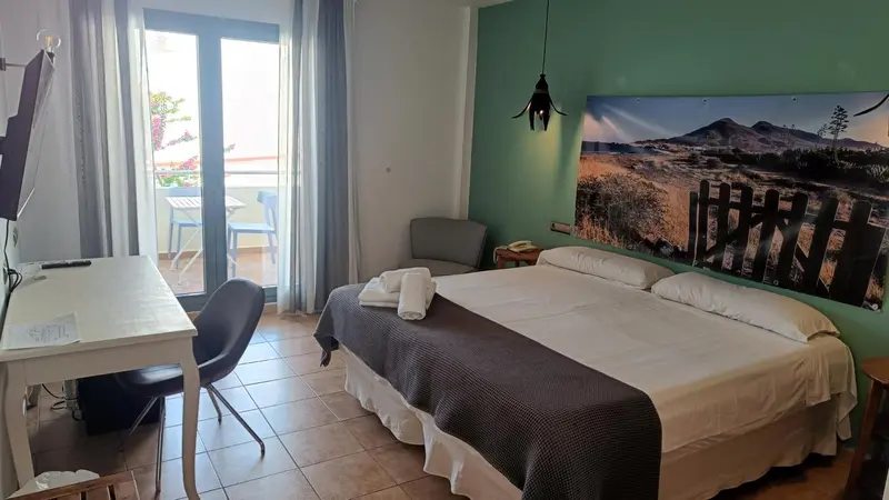 Une chambre lumineuse avec un lit double et un accès à un balcon.