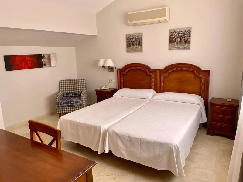 Une chambre lumineuse avec un grand lit et un fauteuil.