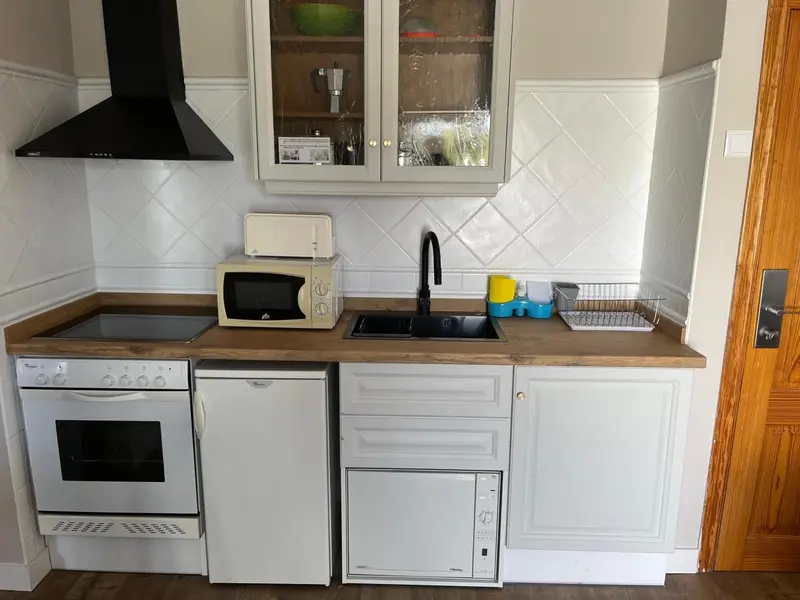 Une cuisine moderne avec des appareils électroménagers blancs et un plan de travail en bois.