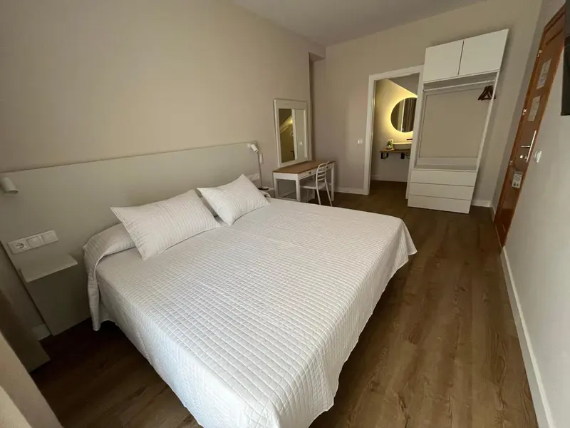 Une chambre lumineuse avec un grand lit et un bureau.