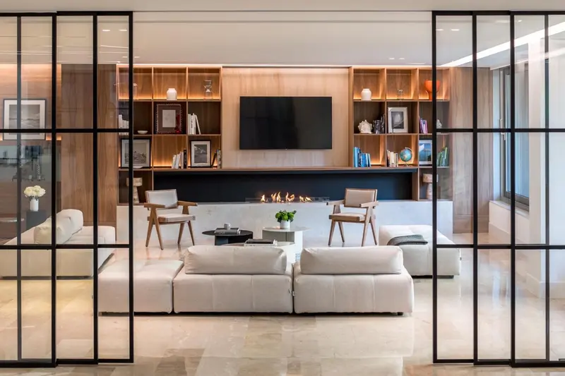 Un salon lumineux avec canapés, fauteuils et une télévision murale.
