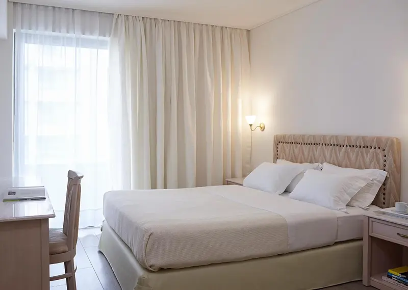 Une chambre lumineuse avec un lit double et un bureau.