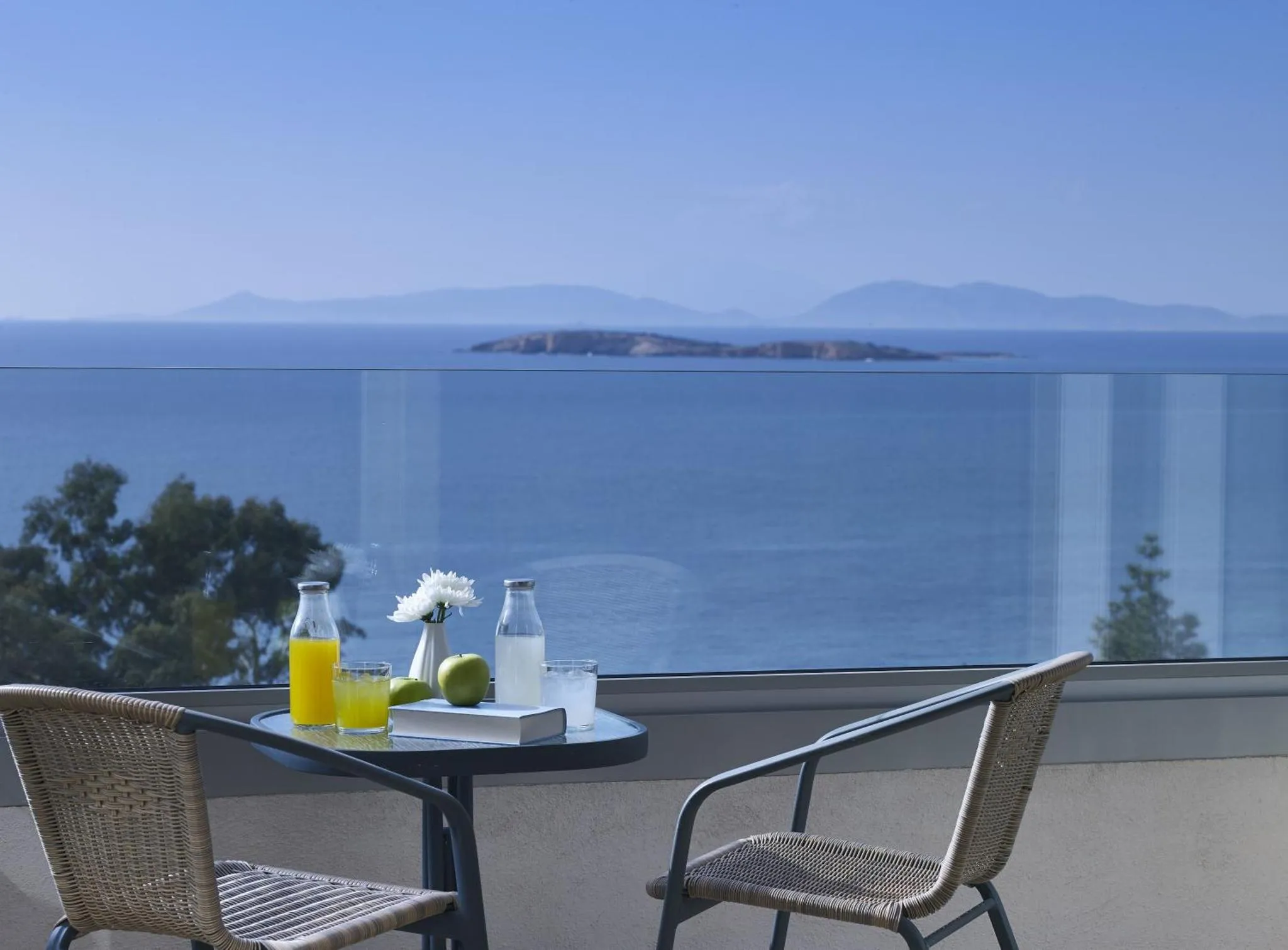 Table et chaises sur une terrasse avec vue sur la mer et une île.