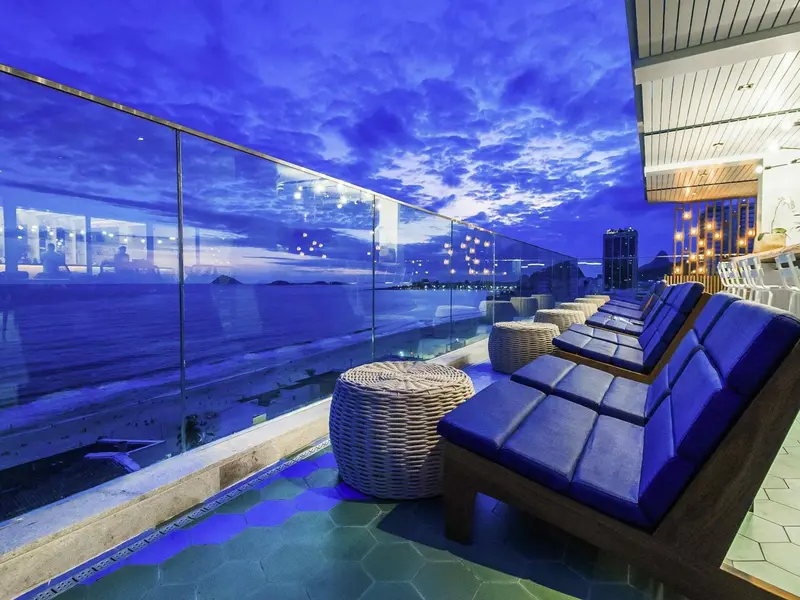 Terrasse avec mobilier d'extérieur et vue sur la mer au coucher du soleil.