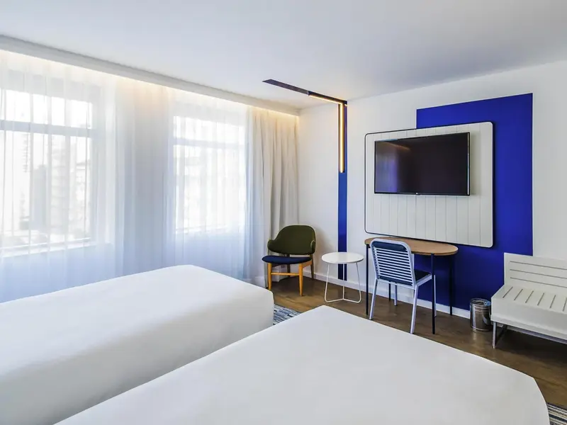 Une chambre lumineuse avec deux lits simples et un coin salon.