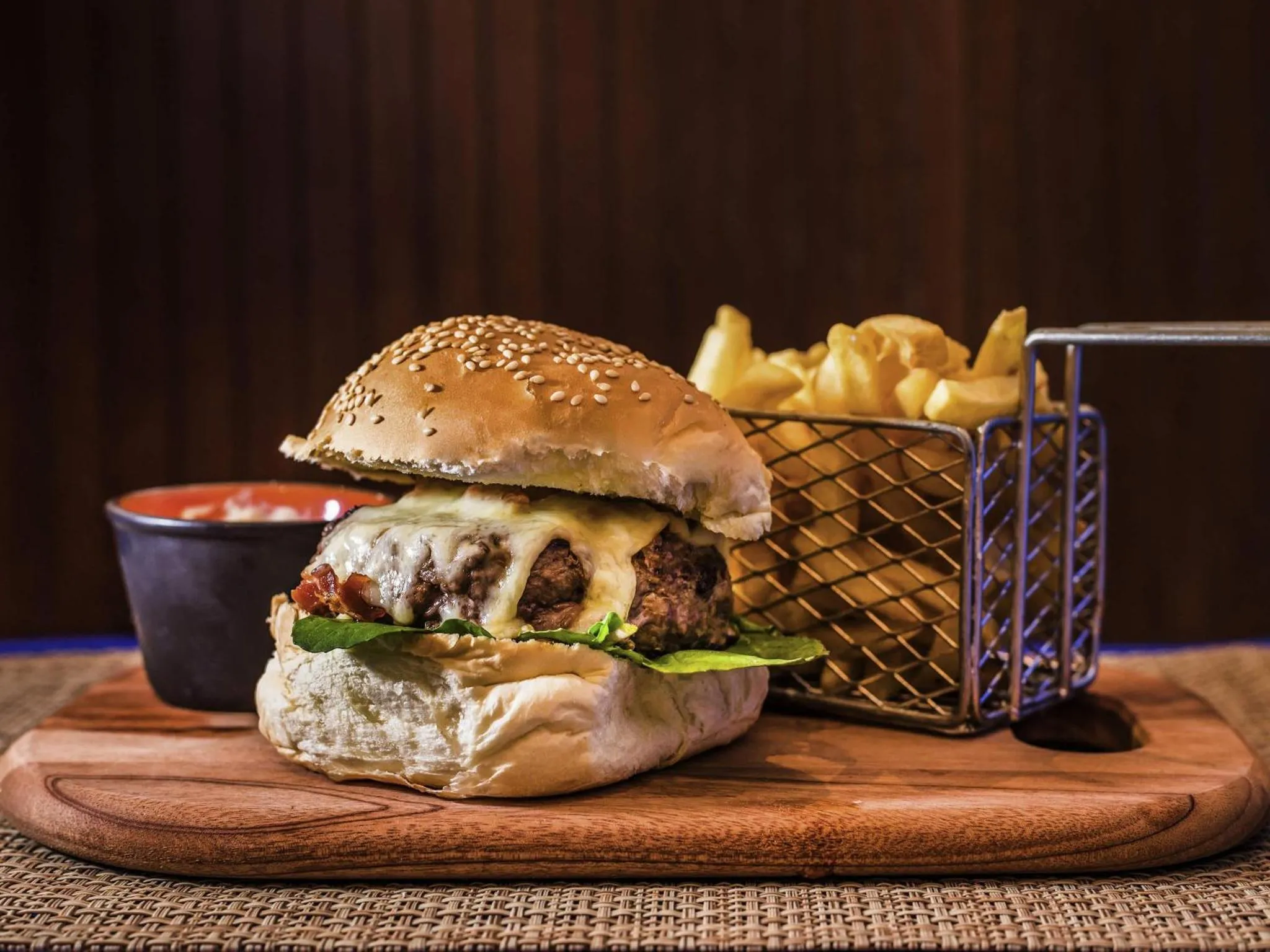 Un hamburger dégoulinant de fromage est servi avec des frites.