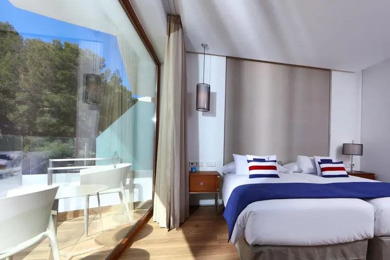 Une chambre lumineuse avec un lit et un accès à une terrasse.