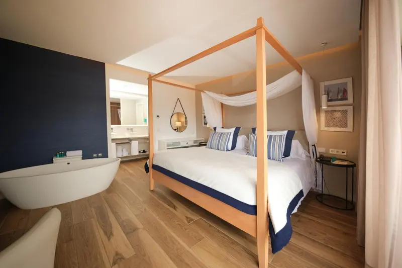 Une chambre lumineuse avec un lit à baldaquin et une baignoire.