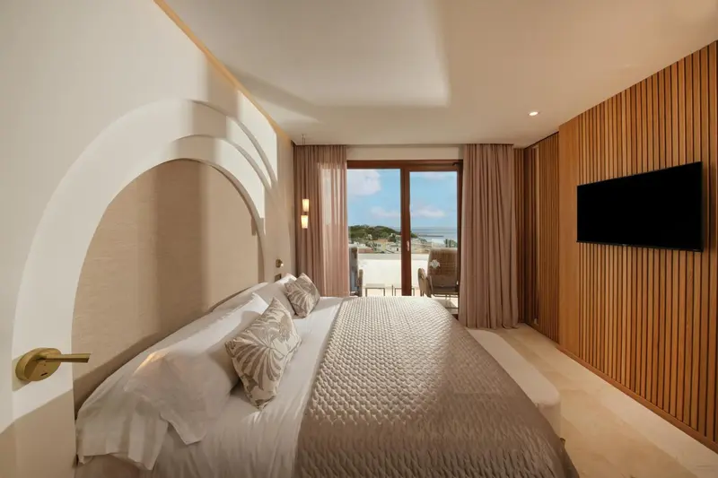 Chambre lumineuse avec un grand lit et une vue sur la mer.