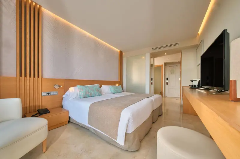 Chambre lumineuse avec un grand lit et un mobilier clair.