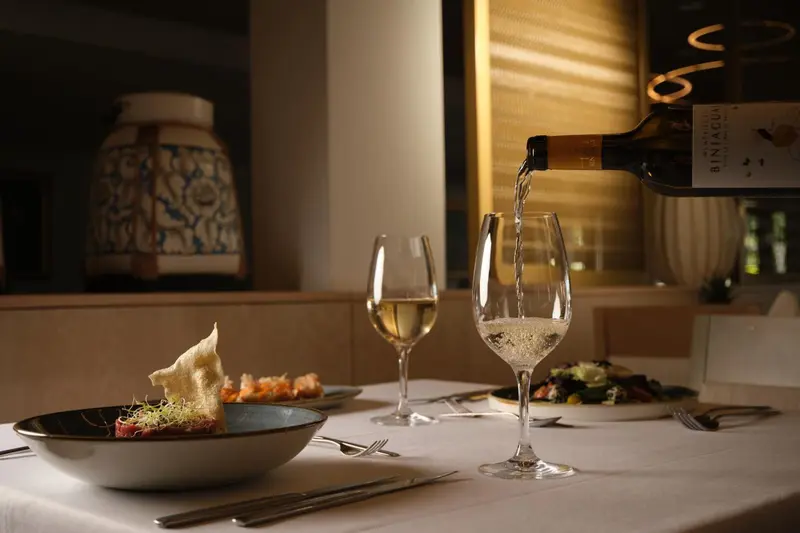 Un verre de vin est rempli au-dessus d'une table dressée avec des plats.