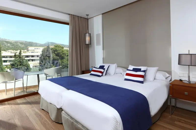 Chambre lumineuse avec un grand lit et vue sur un paysage verdoyant.