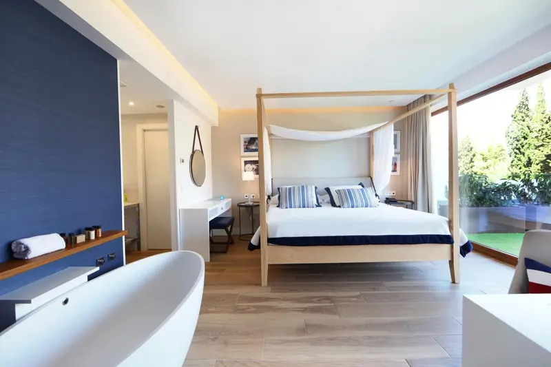 Une chambre lumineuse avec un grand lit à baldaquin et une baignoire.