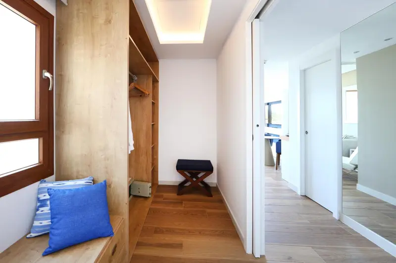 Intérieur clair avec un banc en bois et un placard ouvert.
