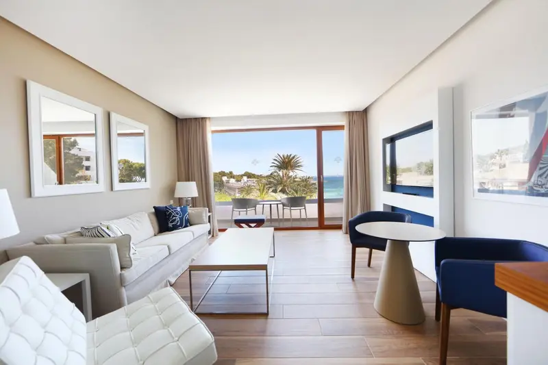 Espace de vie lumineux avec canapé, table basse et vue sur la mer.