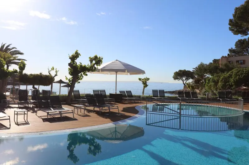 Terrasse avec transats et piscine au bord de la mer.