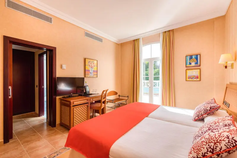 Une chambre lumineuse avec un lit recouvert d'une couverture rouge et un bureau en bois.