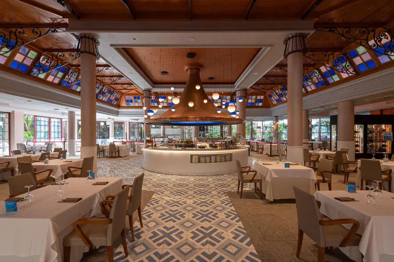 Une salle de restaurant lumineuse avec des tables dressées et un comptoir central.