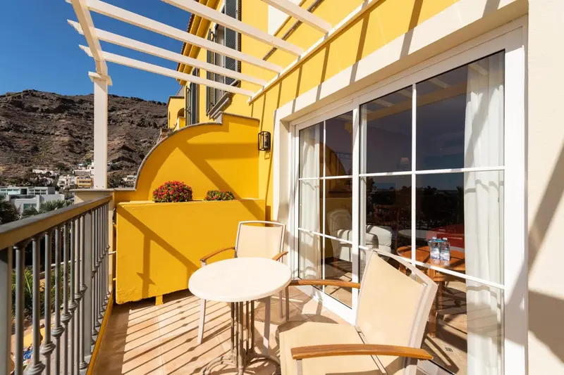 Terrasse ensoleillée avec mobilier de jardin et vue sur le paysage.