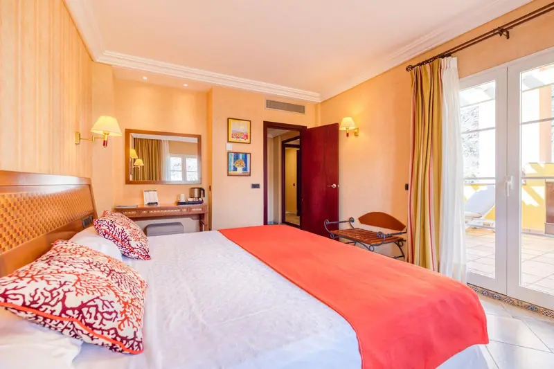 Une chambre lumineuse avec un grand lit recouvert d'une couverture colorée.