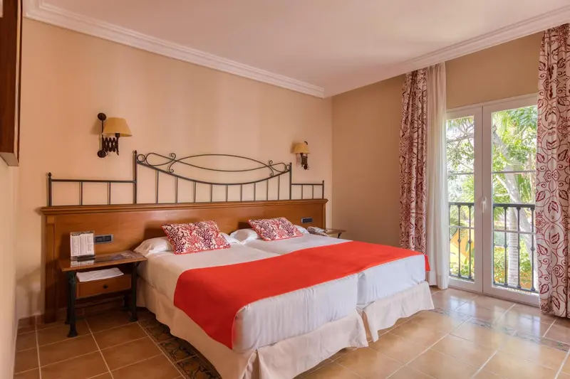 Une chambre lumineuse avec un lit double et un accès à un balcon.