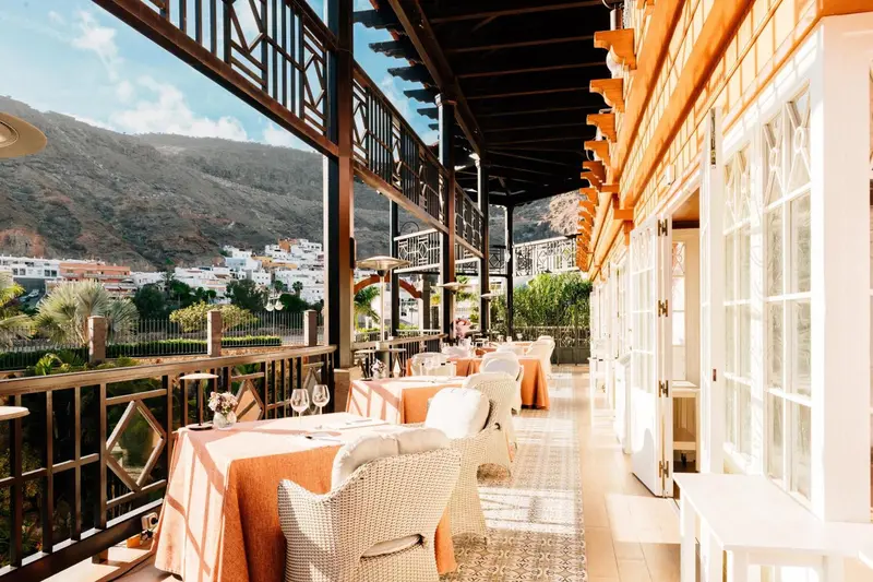 Terrasse ombragée avec tables dressées pour un repas en extérieur.